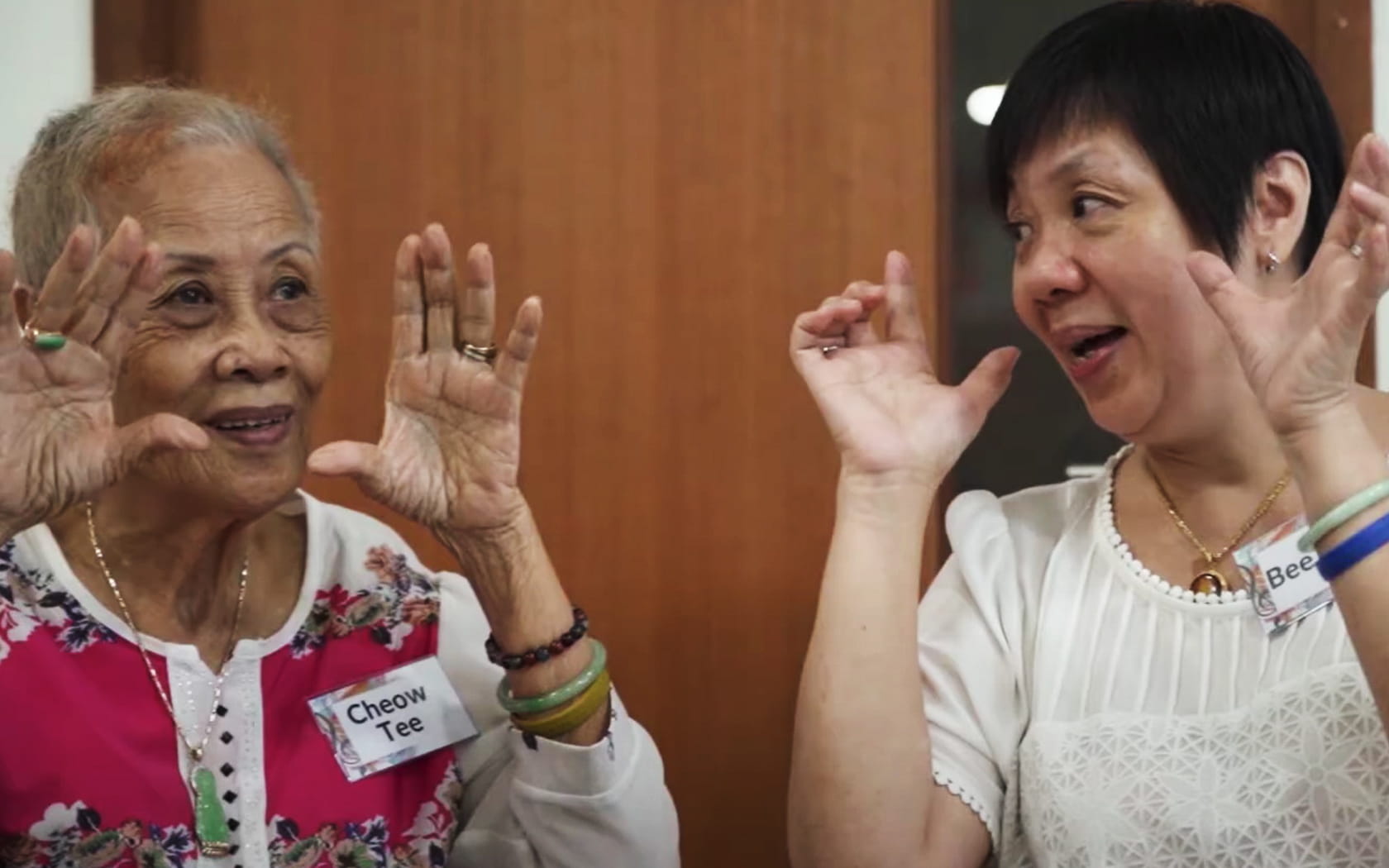 An image of a lady singing happily with a senior.